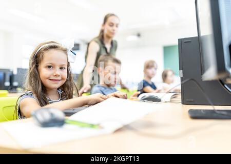 Smiling elementary student sitting in computer class at school Stock Photo