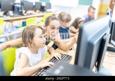 Student using computer with teacher in class at school Stock Photo