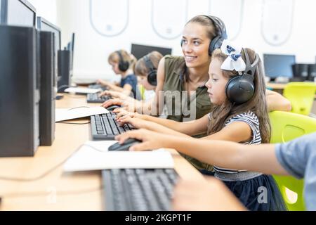Teacher instructing student using computer in class at school Stock Photo