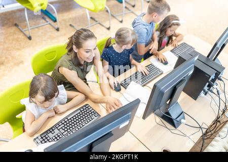 Teacher explaining students sitting at desk in computer class Stock Photo