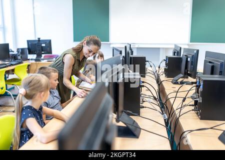 Teacher teaching students through E-learning in class at school Stock Photo