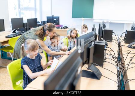 Teacher helping students studying through E-learning at school Stock Photo