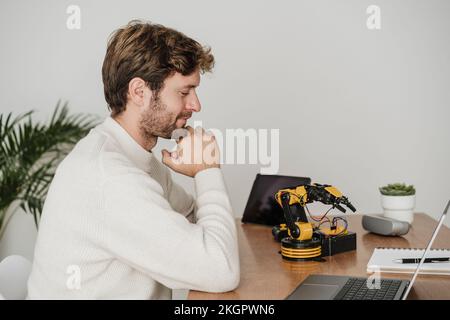 Engineer examining robotic arm on desk in office Stock Photo