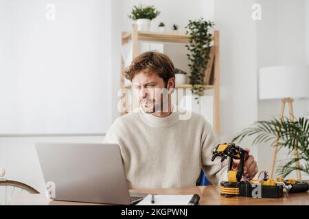 Dedicated businessman using laptop by robotic arm at workplace Stock Photo