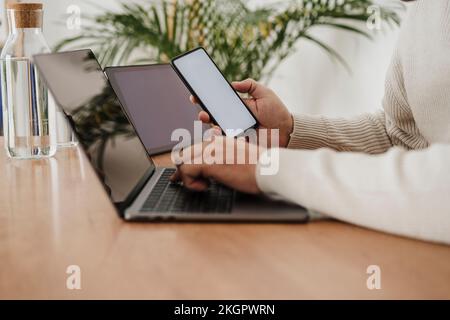 Hands of businessman using laptop and smart phone with blank screens at office Stock Photo