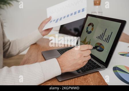 Businessman working on graphs and statistics over laptop at desk in office Stock Photo