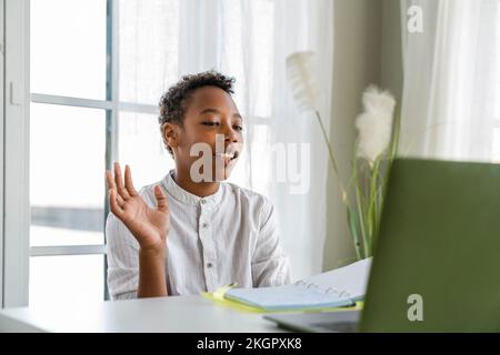 Boy waving on video call through laptop at home Stock Photo