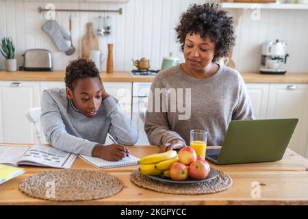 Mother helping son in homework at home Stock Photo