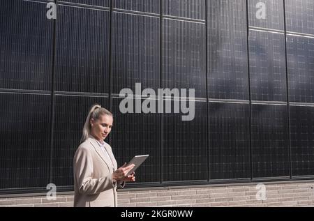 Businesswoman using tablet PC in front of solar panels Stock Photo