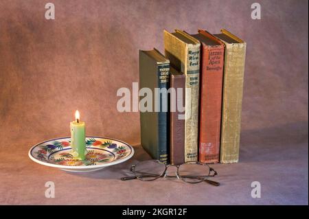 A stack of classic books waiting to be read, including Tarzan of the Apes, The Virginian, Modern Detective Stories, Rogue River Feud, The Wind In The Stock Photo