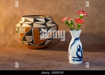 A vase of carnations and an Acoma Indian Pueblo pottery on a dark background. Stock Photo