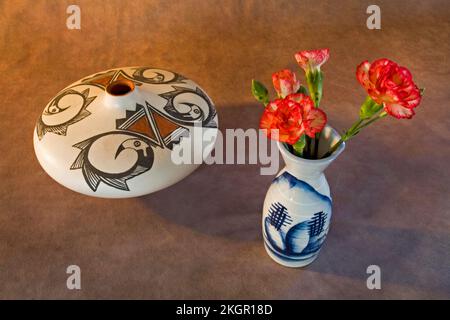 A vase of carnations and an Acoma Indian Pueblo seed storage pot on a dark background. Stock Photo
