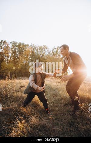 Happy father playing with son on field Stock Photo