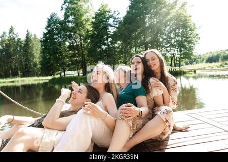 Happy young friends leaning on each other at pier Stock Photo