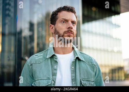 Thoughtful man wearing denim shirt in front of building Stock Photo