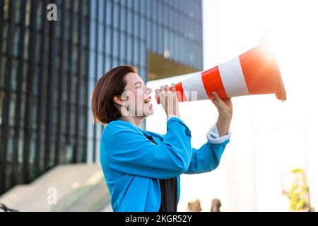 Businesswoman making announcement holding traffic cone Stock Photo