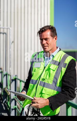 Smiling mature engineer with tablet PC standing by railing Stock Photo
