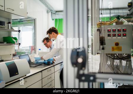 Scientists discussing over laptop in laboratory Stock Photo