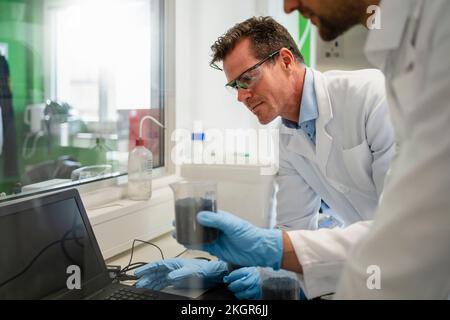 Scientist with colleague using laptop and working on thermolysis experiment in laboratory Stock Photo