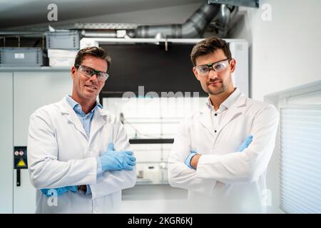 Scientists in lab coats standing with arms crossed in laboratory Stock Photo