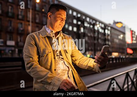 Smiling mature man using smart phone at night Stock Photo