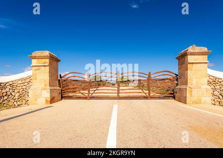 Spain, Balearic Islands, Menorca, Wooden gate in middle of asphalt road Stock Photo