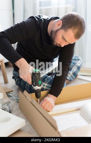 Man using drill machine on table at home Stock Photo