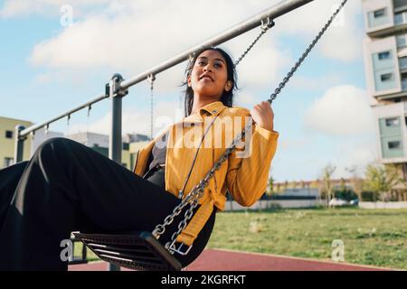 Young woman enjoying on swing at playground Stock Photo