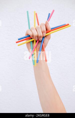 Hand of woman holding colored pencils in front of white wall Stock Photo