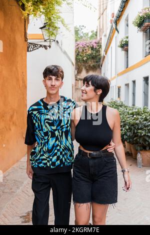 Young man embracing woman walking on footpath Stock Photo
