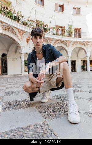 Young man crouching in front of building Stock Photo