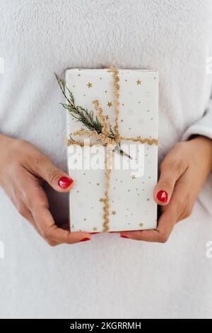 Hands holding wrapped Christmas gift over kraft paper with wide copy ...
