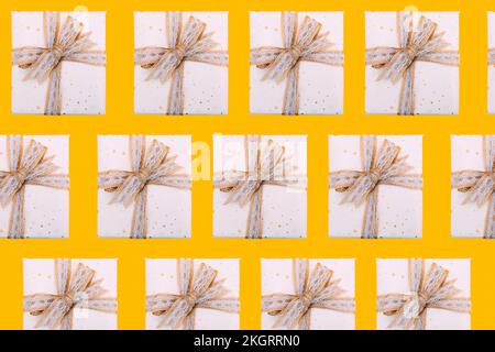 Multiple image of gift boxes wrapped in white paper against yellow background Stock Photo