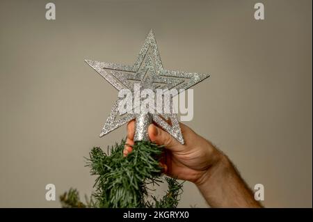Hand of man decorating Christmas tree with silver star Stock Photo