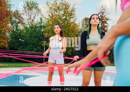 Young woman with friend holding pink string at sports court Stock Photo