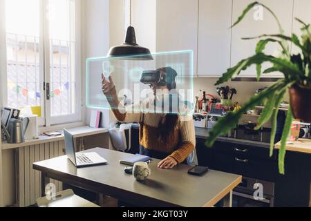 Woman wearing VR glasses touching transparent screen at home Stock Photo
