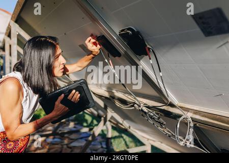 Woman with tablet PC connecting wires of solar panels Stock Photo
