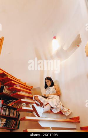 Woman using laptop sitting on staircase at home Stock Photo