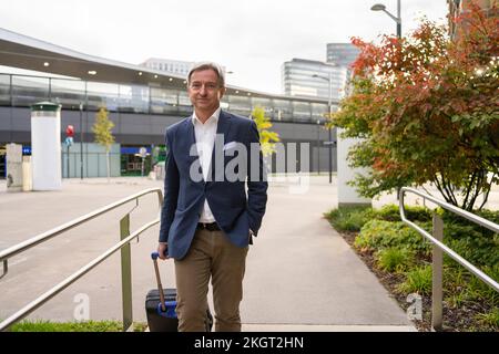 Smiling mature businessman walking with suitcase on footpath Stock Photo