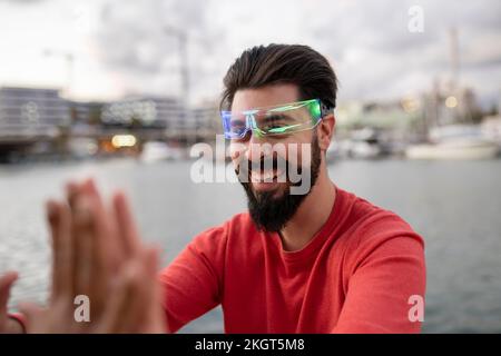 Happy young man wearing smart glasses giving high-five to woman Stock Photo