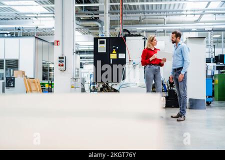 Colleagues talking to each other standing at factory Stock Photo