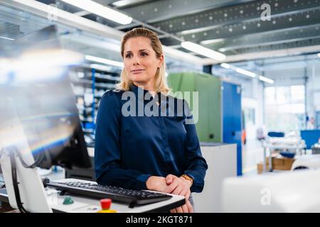 Businesswoman looking at computer screen in industry Stock Photo