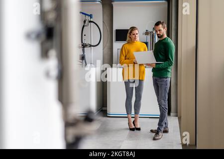 Business colleagues discussing over laptop at factory Stock Photo