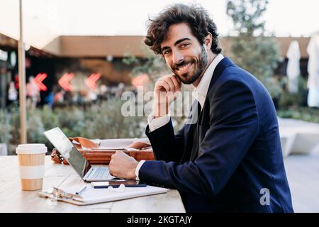 Handsome businessman with laptop at table working from cafe Stock Photo