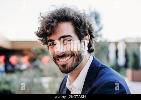 Happy businessman wearing in-ear headphones Stock Photo