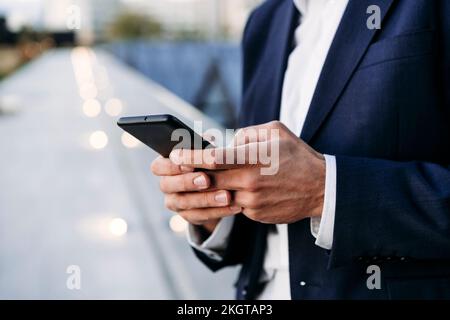 Hands of businessman text messaging through smart phone Stock Photo