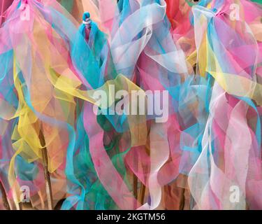 Closeup view of pastel colors textured gauze fabric ribbon strips on bamboo sticks, an offering in thai buddhist temple, Chiang Mai, Thailand Stock Photo