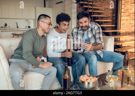Three cheerful guys viewing selfies on the cellphone Stock Photo
