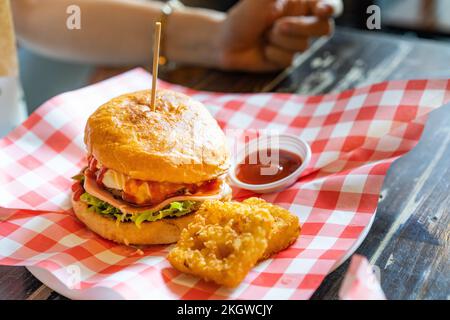 Hamburger set served with hash browns and ketchup on a red and white scotch paper on wooden table looks delicious. Stock Photo