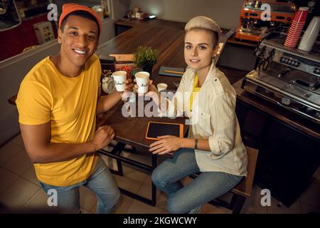 Baristas posing for the camera with caffeinated drinks in hands Stock Photo